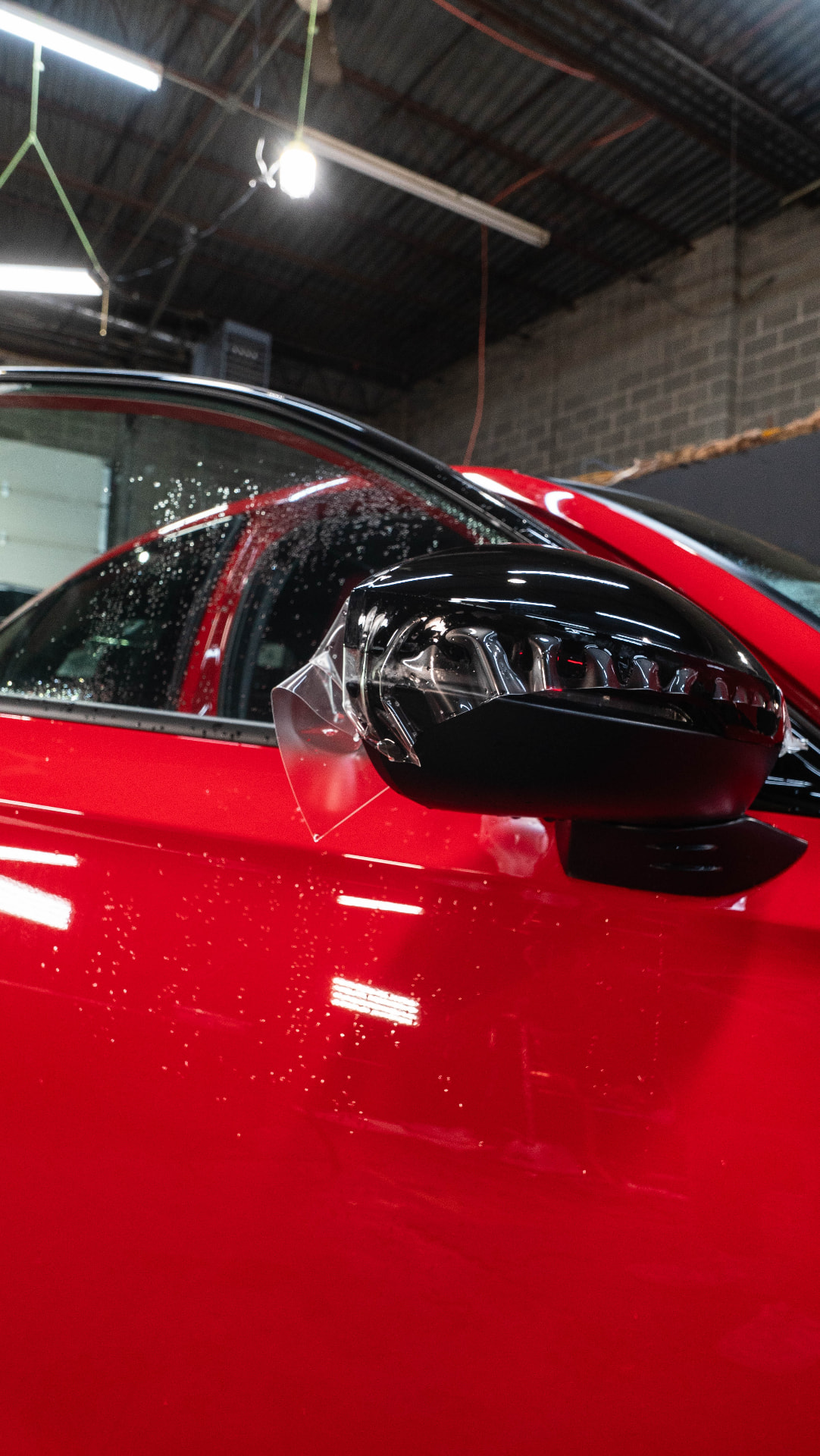 Close-up of a glossy red car door and black mirror after protection work