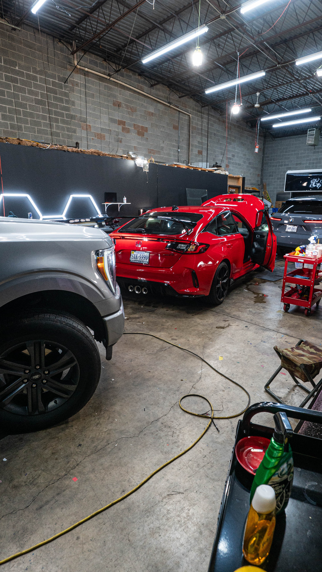 Rear view of a red Honda in the Skyline Customs bay alongside other client vehicles